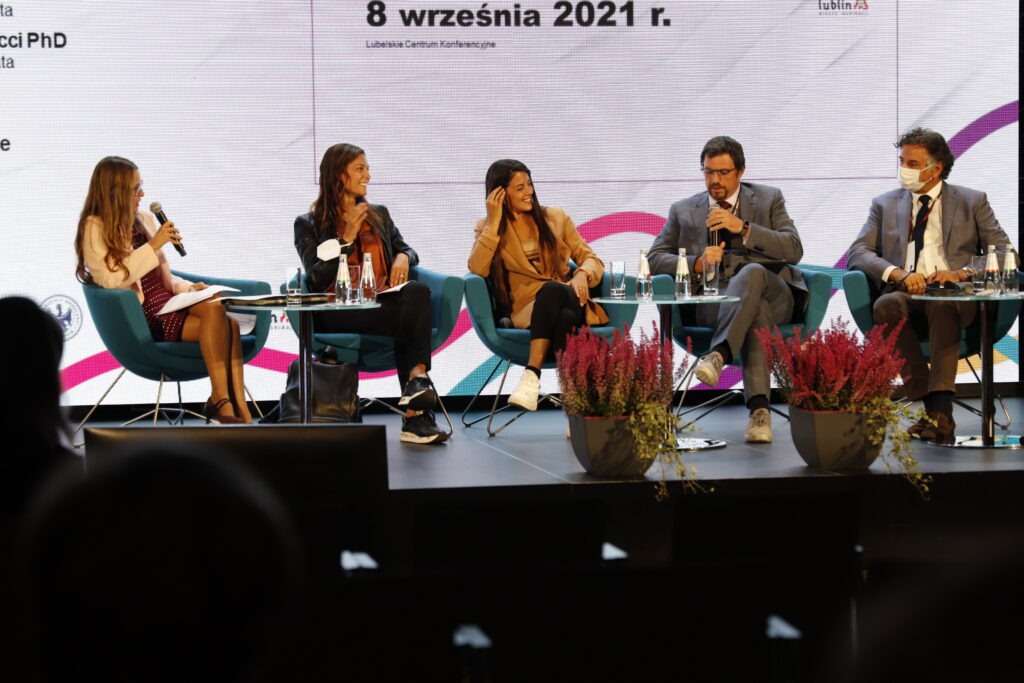 Czterech panelistów (dwie kobiety, dwóch mężczyzn) z zagranicy siedzi na scenie, Prowadząca panel po lewej stronie zadaje pytanie